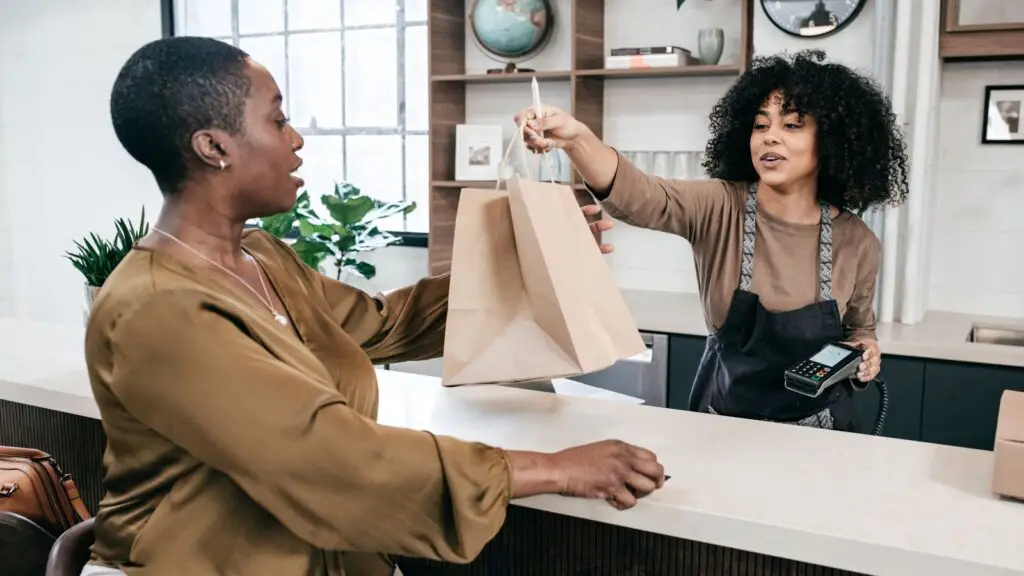 A Shop Keeper in a Retail store handing over a bag to a customer