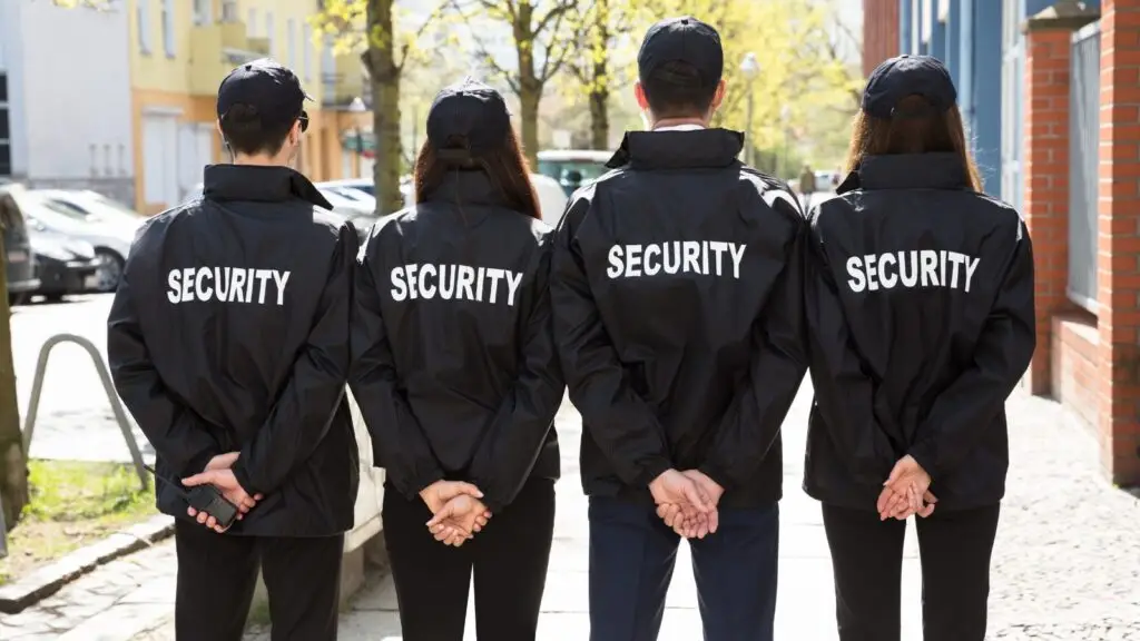 Image of Four Security officers standing with their backs to us while standing on a High Street.
